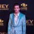 Drake Bell con traje turquesa durante un evento de El rey, Vicente Fernández, frente a un fondo de Caracol Televisión.