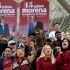 Simpatizantes de Morena levantan los puños frente a lonas por el aniversario 15 del movimiento, con imágenes de Claudia Sheinbaum y Andrés Manuel López Obrador.