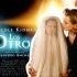 Nicole Kidman junto a una figura cubierta con un velo blanco, frente al cartel de Los otros, película de terror de 2001.