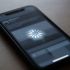 Celular negro sobre una mesa con un símbolo de carga en la pantalla que representa un teléfono trabado.