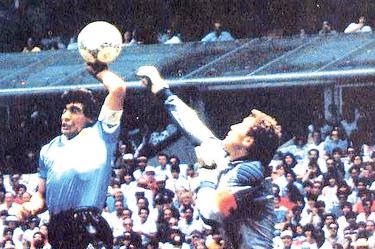 La mano de Dios. El Pelusa salta y toca la pelota con la siniestra, ante la sorpresa del portero inglés Peter Shilton. De nada valió la queja del cancerbero, pues el silbante Ali Bennaceur marcó gol.