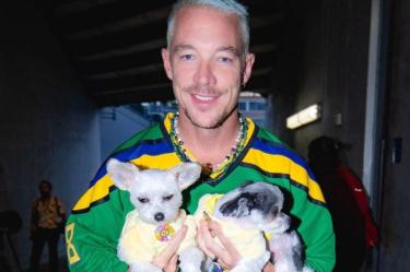 Diplo con jersey verde de hockey cargando dos perritos