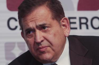 Retrato de Alonso Ancira, ex presidente de AHMSA, en un evento de CANACERO con el logotipo de la cámara al fondo.