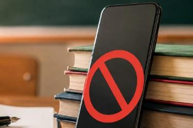 Celular restringido junto a cuaderno y pluma en un salón de clases