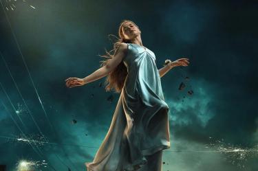 Carrie White con vestido azul claro, suspendida en el aire mientras objetos flotan a su alrededor bajo un cielo oscuro.