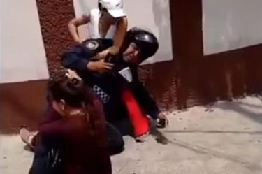 Las mujeres y el policía caen al suelo mientras el motociclista se aleja del lugar. 
