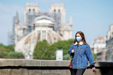 Portando un cubrebocas, una mujer camina por las calles de París, cerca de la catedral de Notre Dame / Foto: Reuters