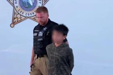 Un policía escolta al niño detenido por amenazar con un tiroteo masivo.