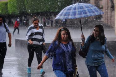 Personas protegiéndose de la lluvia con una sombrilla 