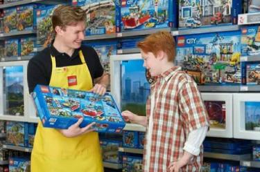 un vendedor de Lego con delantal ofreciendo un producto a un niño