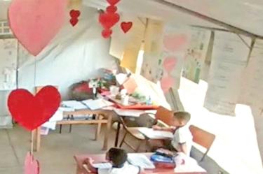 Alumnos tomando clase en una carpa