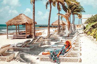 Mujer recostada en un camasro en la playa
