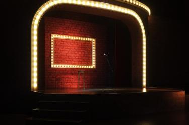 Escenario con luces, micrófono y silla para stand up