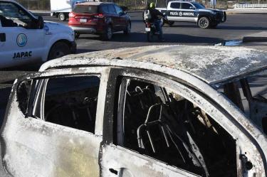 Un auto incendiado y a lo lejos una patrulla