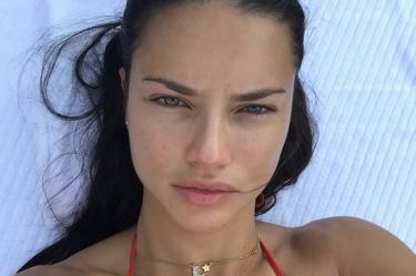 Adriana Lima con bikini en camastro viendo a cámara