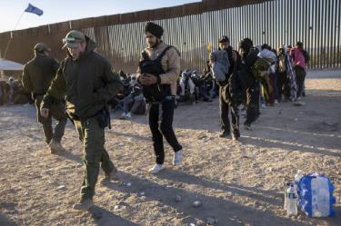 Agentes fronterizos tratando con migrantes en frontera entre Estados Unidos y México.