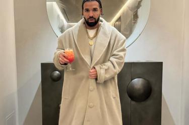 Drake con trenzas y abrigo blanco, copa en mano