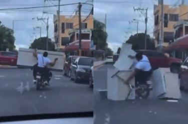 Pareja llevando un mueble en moto 