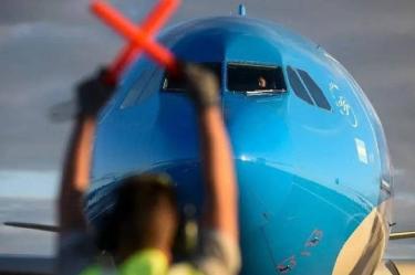 Asistente de vuelo en pista mientras avión aterriza.
