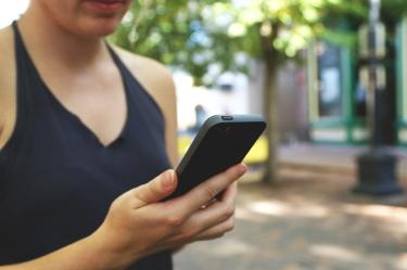 Mujer con celular en la mano caminando en la calle