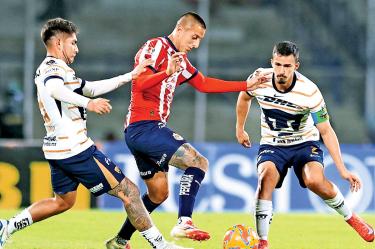 Piojo Alvarado, de Chivas, disputa el balón contra jugadores de Pumas