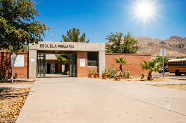 Fachada de una escuela primaria en Chihuahua bajo un sol intenso, ilustrando el adelanto de las vacaciones de verano por la ola de calor.