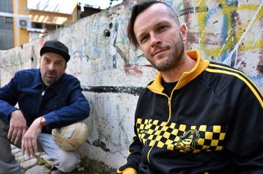 Members of Bosnian Hip-Hop band "Dubioza Kolektiv", Brano Jakubovic (L) and Vedran Mujagic pose with a ball in Sarajevo on June 2, 2026. With brass, guitars, and a music video overflowing with grilled meat, Bosnia has delivered the first World Cup anthem of 2026: "I Am from Bosnia, Take Me to America." the song had already accumulated several million views on different platforms. The song is a cover version of an earlier hit by the Bosnian rock band Dubioza Kolektiv and is rapidly becoming one of the signature songs (anthems) of the 2026 World Cup, which begins on June 11. (Photo by ELVIS BARUKCIC / AFP)
