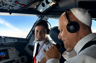 El papa León XIV con auriculares conversa con una piloto en la cabina de un avión durante el trayecto entre Madrid y Barcelona.