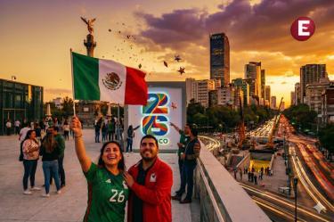 Pareja de aficionados celebrando con la bandera de México frente al Ángel de la Independencia y un letrero del Mundial 2026 al atardecer en la Ciudad de México.