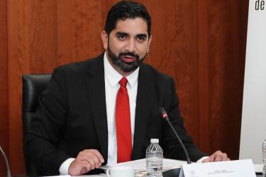 Roberto Lazzeri exponiendo su plan de trabajo diplomático con un bolígrafo en la mano; de fondo, un cartel de la Primera Reunión de la Primera Comisión en junio de 2026.