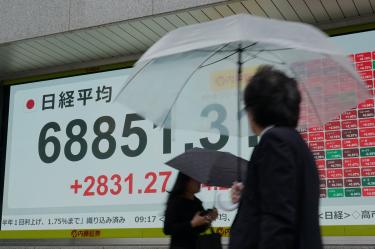Peatones pasan junto a un panel electrónico de cotizaciones que muestra el índice Nikkei de la Bolsa de Tokio en Tokio en junio.