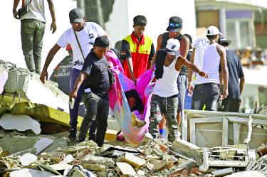 Un grupo de personas traslada a una mujer sobre una manta entre los escombros de un edificio de apartamentos dañado tras el terremoto en Catia La Mar, estado de La Guaira —a unos 30 km al noroeste de Caracas—.
