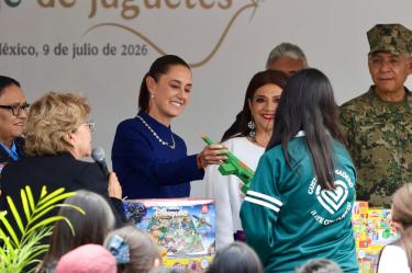 La Presidenta Claudia Sheinbaum y Clara Brugada intercambiando una pistola de juguete verde por juegos de mesa didácticos con una niña durante el evento Sí al desarme, Sí a la paz.