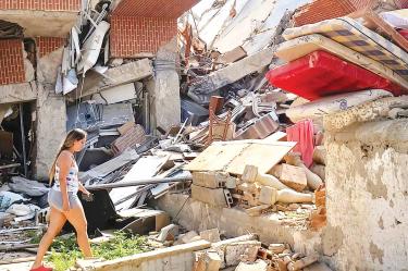 Una venezolana camina entre los escombros de un edificio destruido por los sismos.