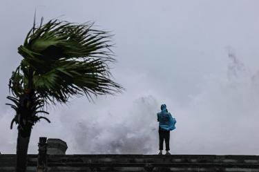 A person looks on as large waves crash against the coast as Typhoon Bavi passes off northeastern Taiwan, in Keelung on July 11, 2026. (Photo by I-Hwa Cheng / AFP)