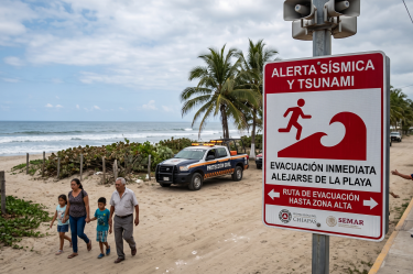 Cartel de alerta sísmica y evacuación por tsunami en una playa de Chiapas tras el sismo de magnitud 7.4.