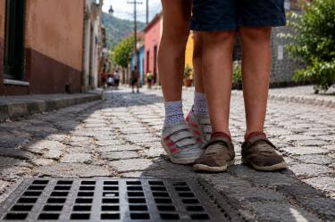 Dos niñas caminan por una calle empedrada, imagen representativa de menores en condición de orfandad y la necesidad de apoyo integral.