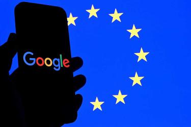 Una persona sostiene un celular con el logo de Google y al fondo la bandera de la UE.