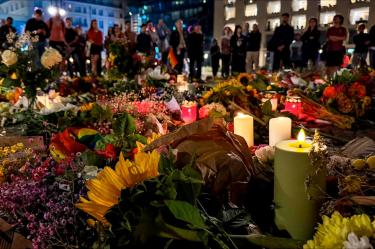 Se encienden velas entre flores en memoria de las víctimas frente a la Puerta de Brandeburgo, en Berlín
