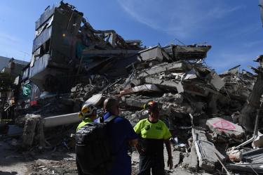 Un miembro de un equipo de rescate busca supervivientes entre los escombros de un edificio