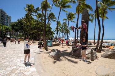 Personas se toman fotografías frente a la estatua de Duke Kahanamoku en la playa de Waikiki