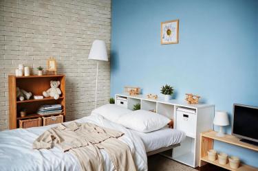 Una recámara con cama blanca, iluminación y espacios de almacenamiento muestra elementos del entorno que pueden favorecer un ambiente de descanso.