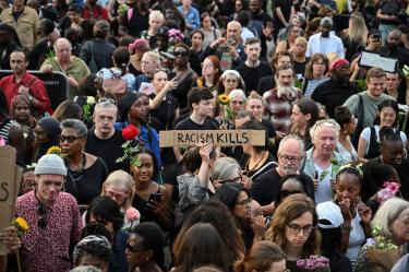 Asistentes participan en una vigilia por Jason Arday en Trafalgar Square, Londres, con flores y pancartas contra el racismo.