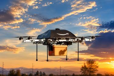 Un dron de Amazon equipado para reparto aéreo transporta un paquete bajo el sistema Prime Air, en una imagen ilustrativa del servicio.