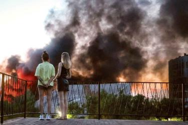 Dos jóvenes observan el humo que se eleva sobre Kiev durante un ataque con drones rusos.