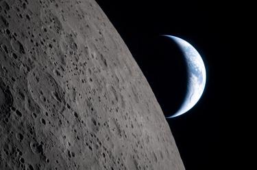 La Luna ocupa el primer plano mientras la Tierra aparece parcialmente iluminada al fondo, fotografiada desde la nave Orion.