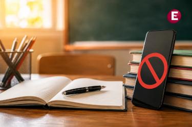 Celular restringido junto a cuaderno y pluma en un salón de clases