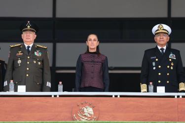 Claudia Sheinbaum en el centro del presídium formal, flanqueada por el General Ricardo Trevilla Trejo (SEDENA) y el Almirante Morales Ángeles (SEMAR) en la ceremonia del Heroico Colegio Militar Tlalpan. El Escudo Nacional está visible al frente.