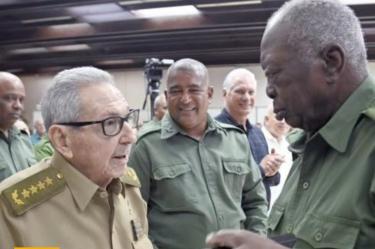 Hombre mayor con uniforme verde olivo conversa con un militar durante un acto del Ministerio del Interior en Cuba.