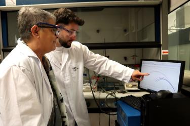 Nieves Casañ-Pastor y Marc Mosqueda, investigadores del CSIC, observan datos de pruebas sobre baterías en un laboratorio.